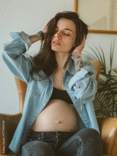 Pregnant woman sitting on a chair with hands covering her head feeling pain
