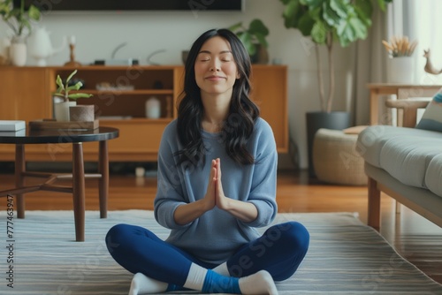 A young woman is sitting on the floor in a meditation pose with a smile on her face. Her face radiates calmness and peace, and her smile speaks of an inner joyful state