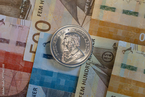 Silver coin, Krugerrand with Norvegian Krone notes in background. © PIOTR