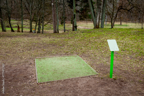 A green recreational area  for outdoor disc golf in erly spring. Drop zone with artificial grass and map. Outdoor recreational sports equipment, no people around. Vilce Manor, Latvia, Baltic. photo
