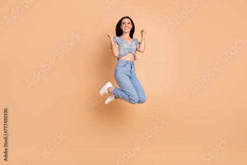 Photo of cheerful crazy good mood woman wear blue trendy clothes jump up yes win isolated on beige color background