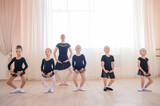 Children's ballet school. Caucasian woman teaching ballet to little girls. 