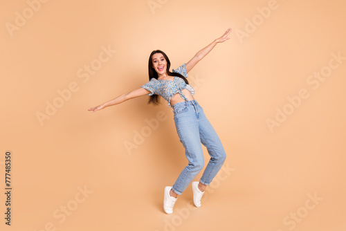 Photo of funny funky lovely woman dressed blue trendy clothes fly air empty space isolated on beige background