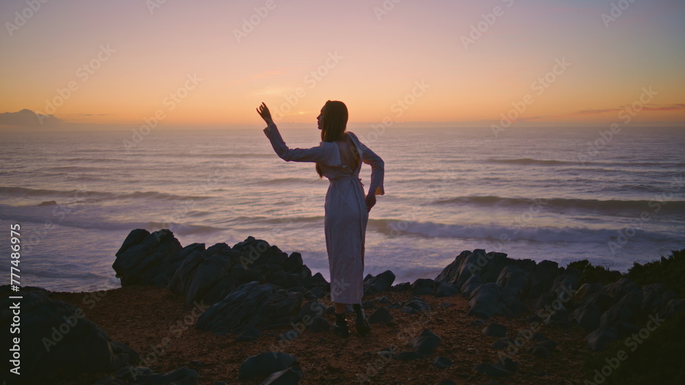 Lady silhouette dancing sunset cliff bending flexible body dance hill back view