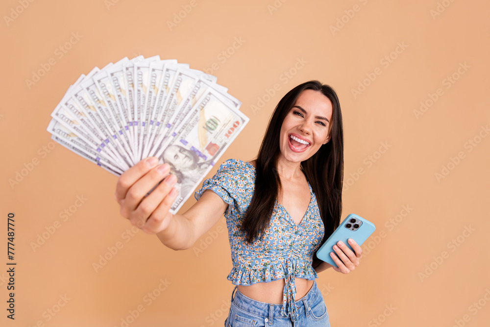 Photo of crazy cheerful woman wear blue trendy clothes showing cash lottery million isolated on beige color background