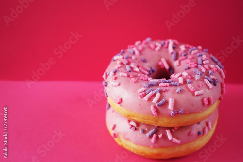 Donuts in pink glaze with sprinkles on a pink background