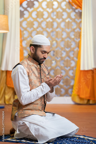 Vertical shot of indian muslim man doing holy namaz or Salah at home during ramdan festival - concept tredition, culture and festive celebration. photo