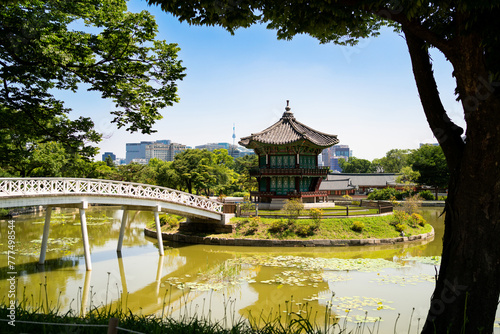 South Korea, Seoul. Gyeongbokgung palace area garden and park. Hyangwonjeong pavilion and bridge. City skyline in the background. Summer travel and tourist attraction. Beautiful Korean landscape. photo