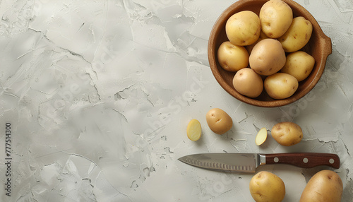 Bowl with raw potatoes and knife on light background photo