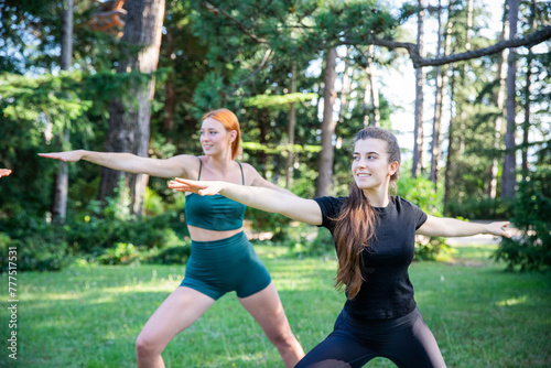 Two women are doing yoga in a park during a summer day, healthy lifestyle