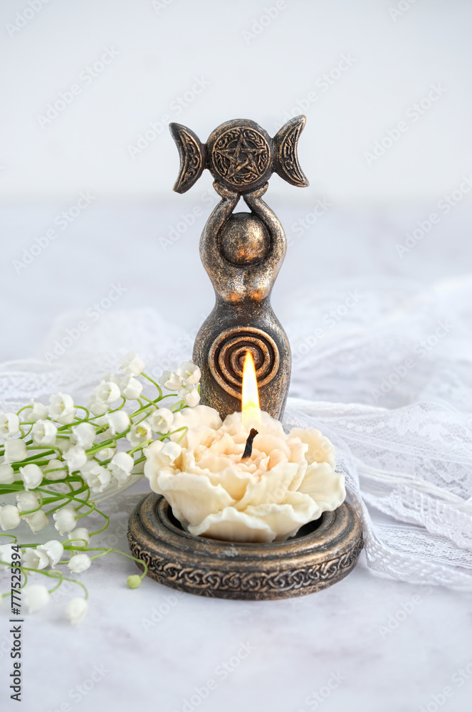 amulet of Triple Goddess figurine, floral candle and lilies of the ...