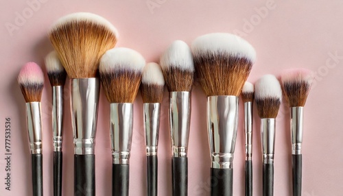 Makeup brushes set in row. Professional makeup tools on pastel pink background. Set of glamour make up brushes