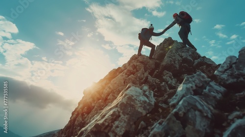 Two climbers helping each other on a rocky mountain at sunset
