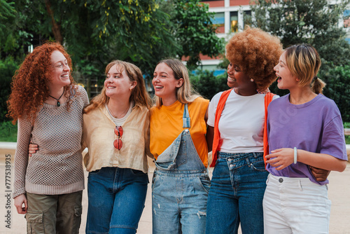 Group of joyful young women, laughing and enjoying a weekend trip. Real cool girls walking embracing with a smile. Happy female friends having fun together outside. Generation of unity and vitality