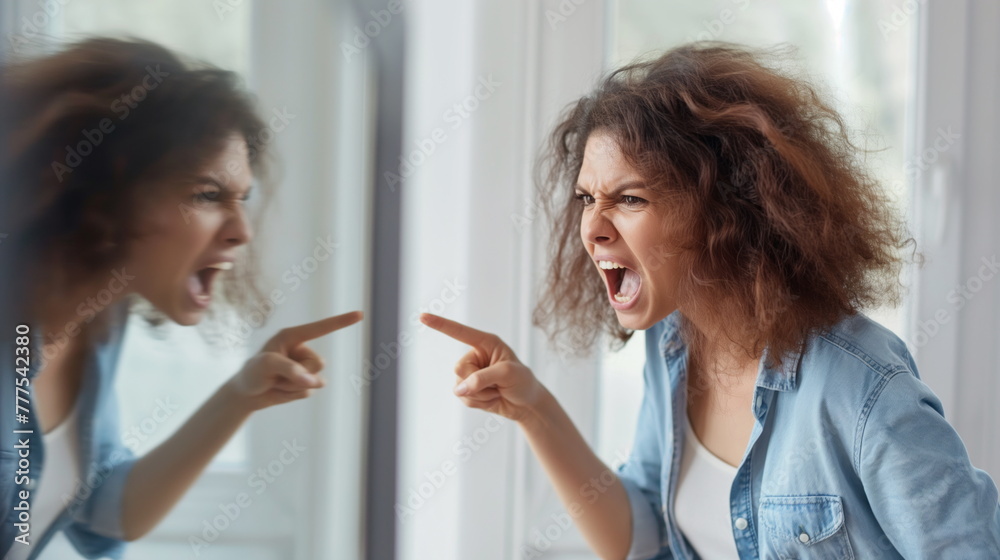 Person is caught in a moment of frustration, shouting and pointing angrily at their own reflection in a mirror