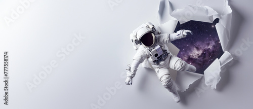 An astronaut reaches out from ripped paper towards an enchanting galaxy, depicting ambition and the human quest for knowledge