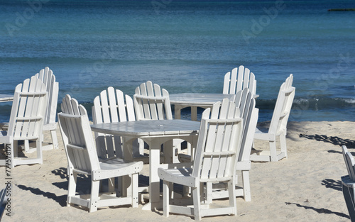 White Wooden Tables and Chairs Along the Beach © dejavudesigns