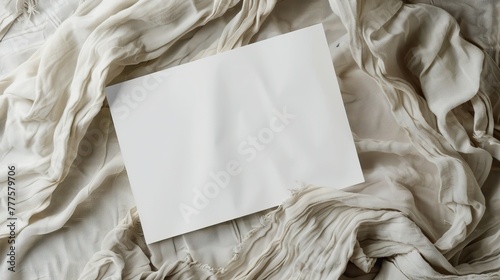 A blank white paper rests on a textured, crumpled fabric photo