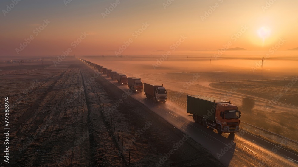 Obraz premium Aid convoy of trucks on a mission at dawn heading through a misty landscape