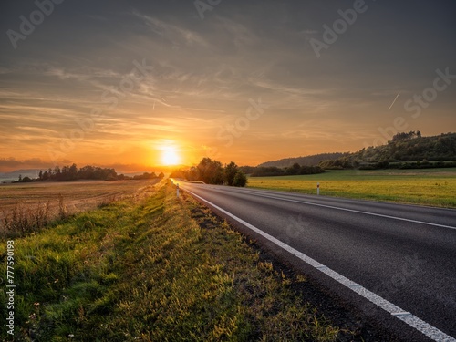Empty asphalt road in a rural landscape at sunset
