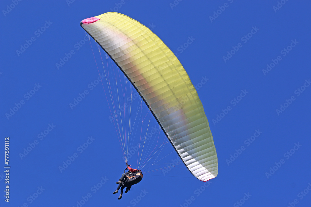 Tandem Paraglider flying in a blue sky Tandem Paraglider flying in a blue sky