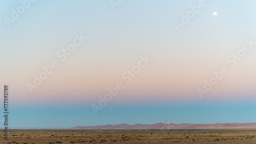 Blick in die Weite des Namib-Naukluft Nationalparks, Morgendämmerung mit Vollmond am Himmel photo