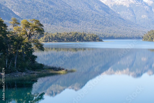 Calm and relaxing horizontal view of mountain range full of dense forests reflecting onto a lake's crystaline tranquil water wallpaper