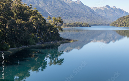 Calm and relaxing horizontal view of mountain range full of dense forests reflecting onto a lake's crystaline tranquil water wallpaper