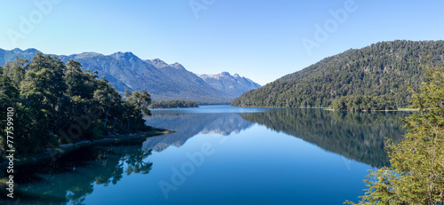 Calm and relaxing horizontal view of mountain range full of dense forests reflecting onto a lake's crystaline tranquil water wallpaper