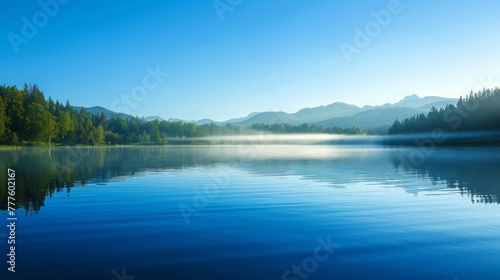 A peaceful lake with large   and a thin mist rising from the surface. At dawn  under the clear blue sky  the forest is surrounded by trees