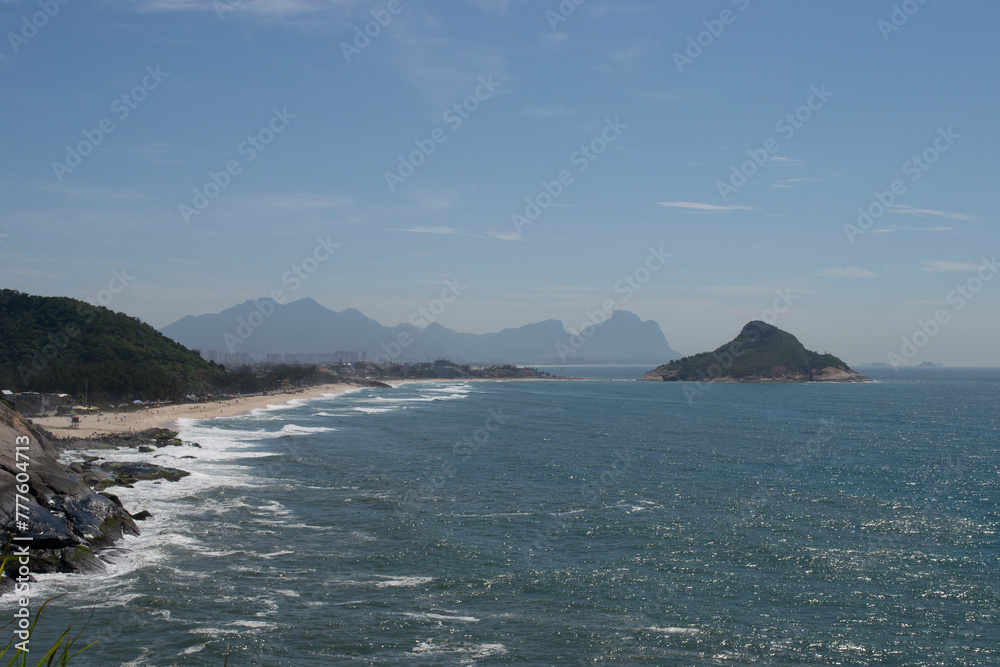 Panoramic view of the mountains, vegetation and the ocean with clear blue waters of Praia do Pontal, located in the city of Rio de Janeiro.