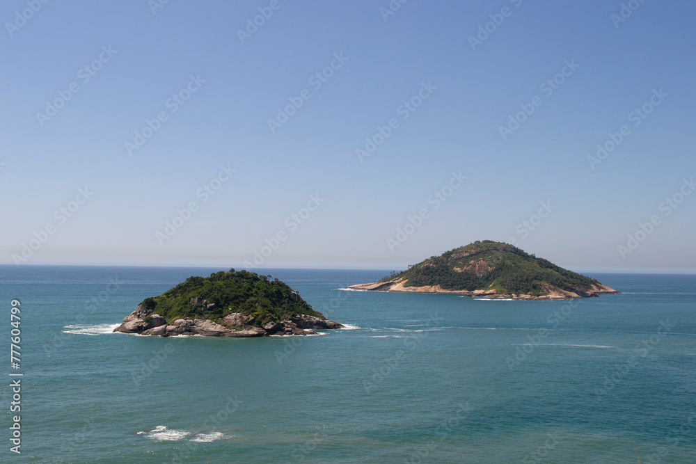 Mountains, vegetation and the ocean with clear blue waters of Praia de Grumari, located in the city of Rio de Janeiro.