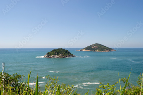 Mountains, vegetation and the ocean with clear blue waters of Praia de Grumari, located in the city of Rio de Janeiro.