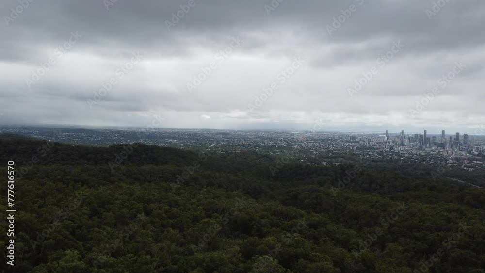 Drone ascending over a mountain to reveal a large Australian city suburbs and the city skyline with skyscrapers Drone ascending over a mountain to reveal a large Australian city suburbs and the city skyline with skyscrapers