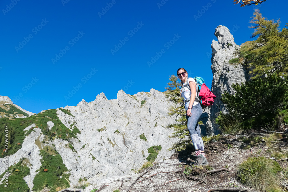 Hiker woman with panoramic view of majestic mountain ridges in wild Hochschwab massif, Styria, Austria. Scenic hiking trail along unique rock formations. Wanderlust in remote Austrian Alps in summer