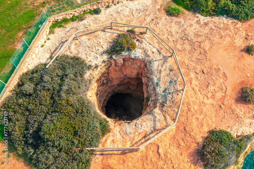 Sinkhole in the ground. Rocky seascape near Praia da Marinha beach in the Algarve region in the Atlantic Ocean, Portugal, Europe
