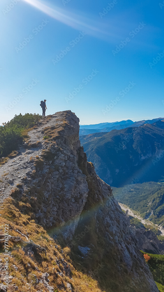 Hiker man standing on mountain summit with panoramic view of majestic Hochschwab massif, Styria, Austria. Idyllic hiking trail in remote Austrian Alps. Sense of escapism, peace, personal reflection