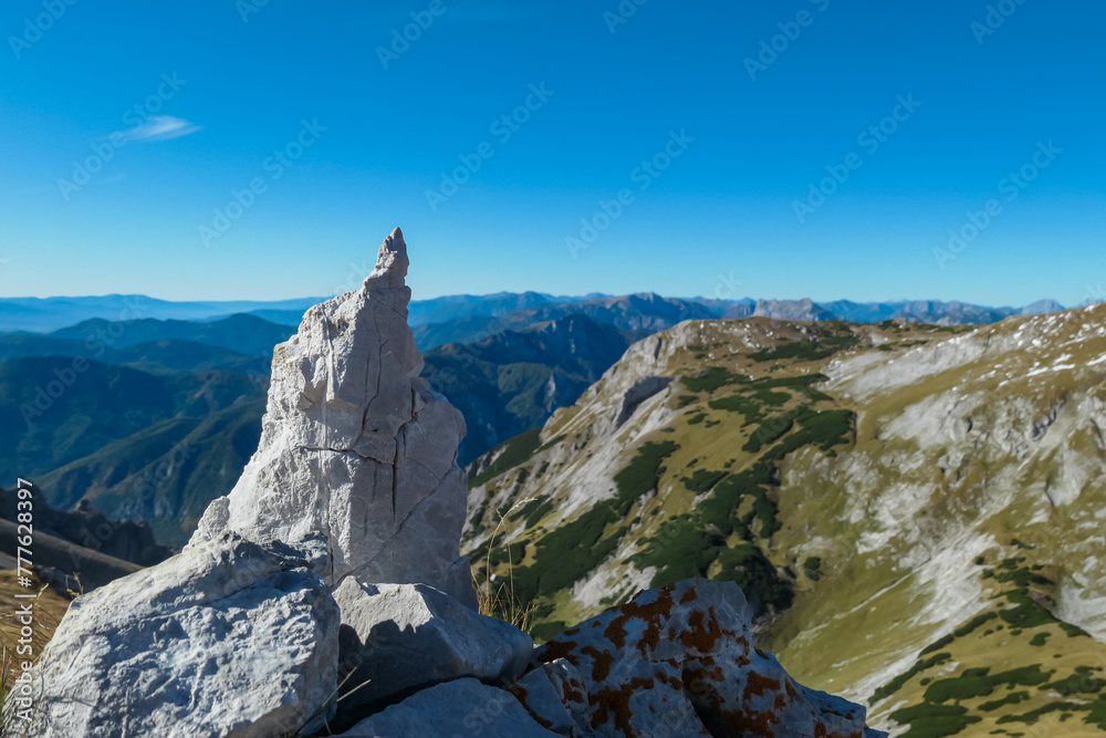 Selective focus on rock formation with scenic view mountain peaks of wild Hochschwab massif, Styria, Austria. Wanderlust in remote Austrian Alps on sunny day. Goal achieving. Alpine meadow. Escapism