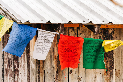 Colorful Buddhist prayer flags hanging wood house eaves photo