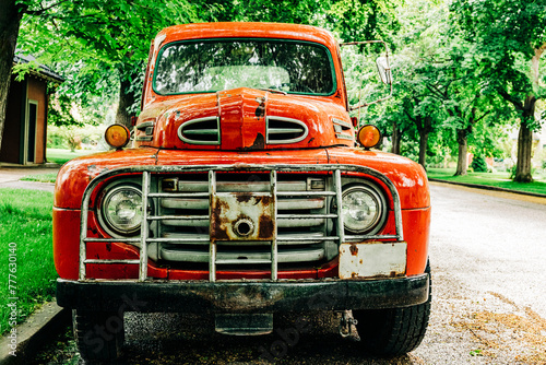 Vintage orange truck parked on tree lined street © Cavan