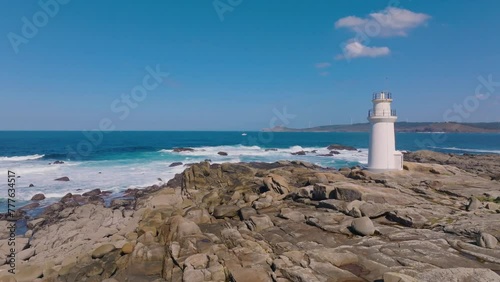 Drone pull-back shot of the Muxia lighthouse on the rocky coastline of Muxia in A Coruna, Spain.