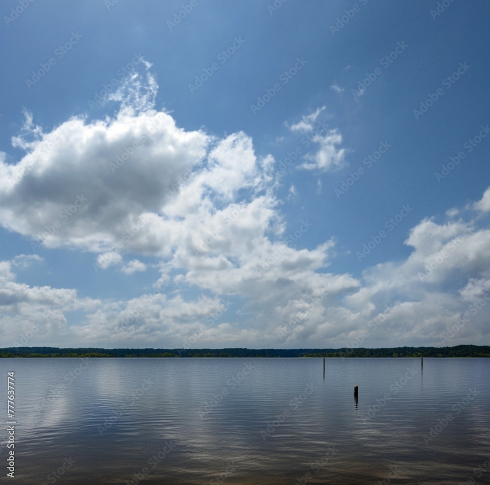 View of Lake Conroe with calm waters under a blue sky and fluffy white clouds. Texas