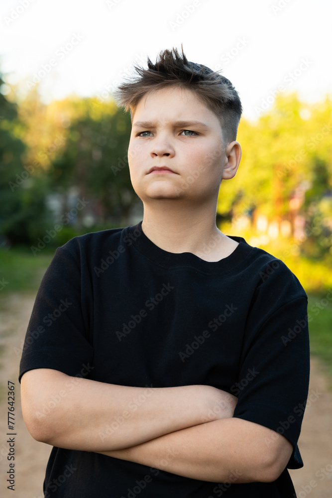 Portrait serious teenager with fresh haircut, black tee, crossed arms Portrait serious teenager with fresh haircut, black tee, crossed arms