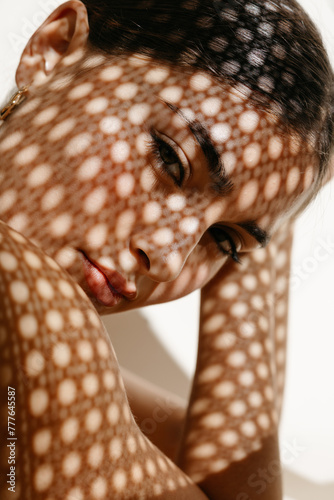 Woman in red lips touching head under spotted light shadow photo
