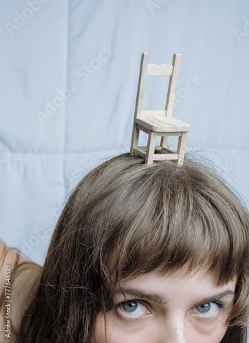 Miniature chair on woman's head. Alice in wonderland homage.  photo