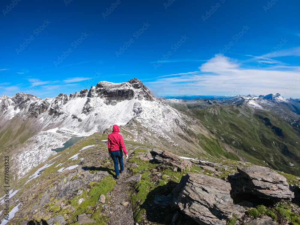 Hiker woman with scenic view of majestic mountain peaks of High Tauern seen from Feldseekopf, Carinthia Salzburg, Austria. Idyllic hiking trail in Goldberg group in wild Austrian Alps. Wanderlust