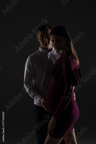 portrait of a pregnant couple on a black background, pregnant couple close up