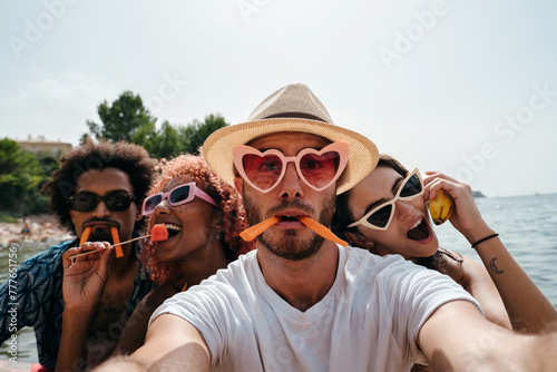 Young people at the beach taking a funny selfie eating photo