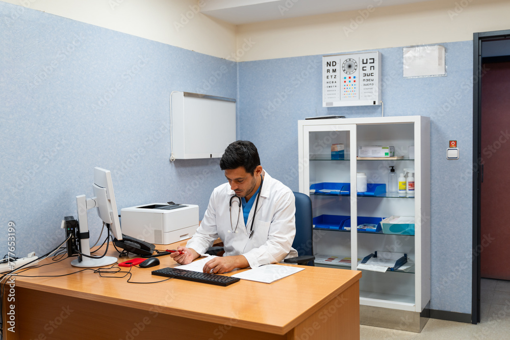 doctor writing on clipboard while sitting at desk in clinic