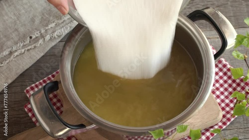 Preparation of dandelion syrup or honey - pouring sugar into water in which fresh dandelion flowers have been macerated photo